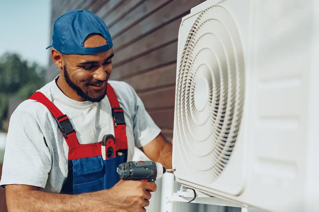 Technician performing air conditioning installation on an outdoor condenser unit.